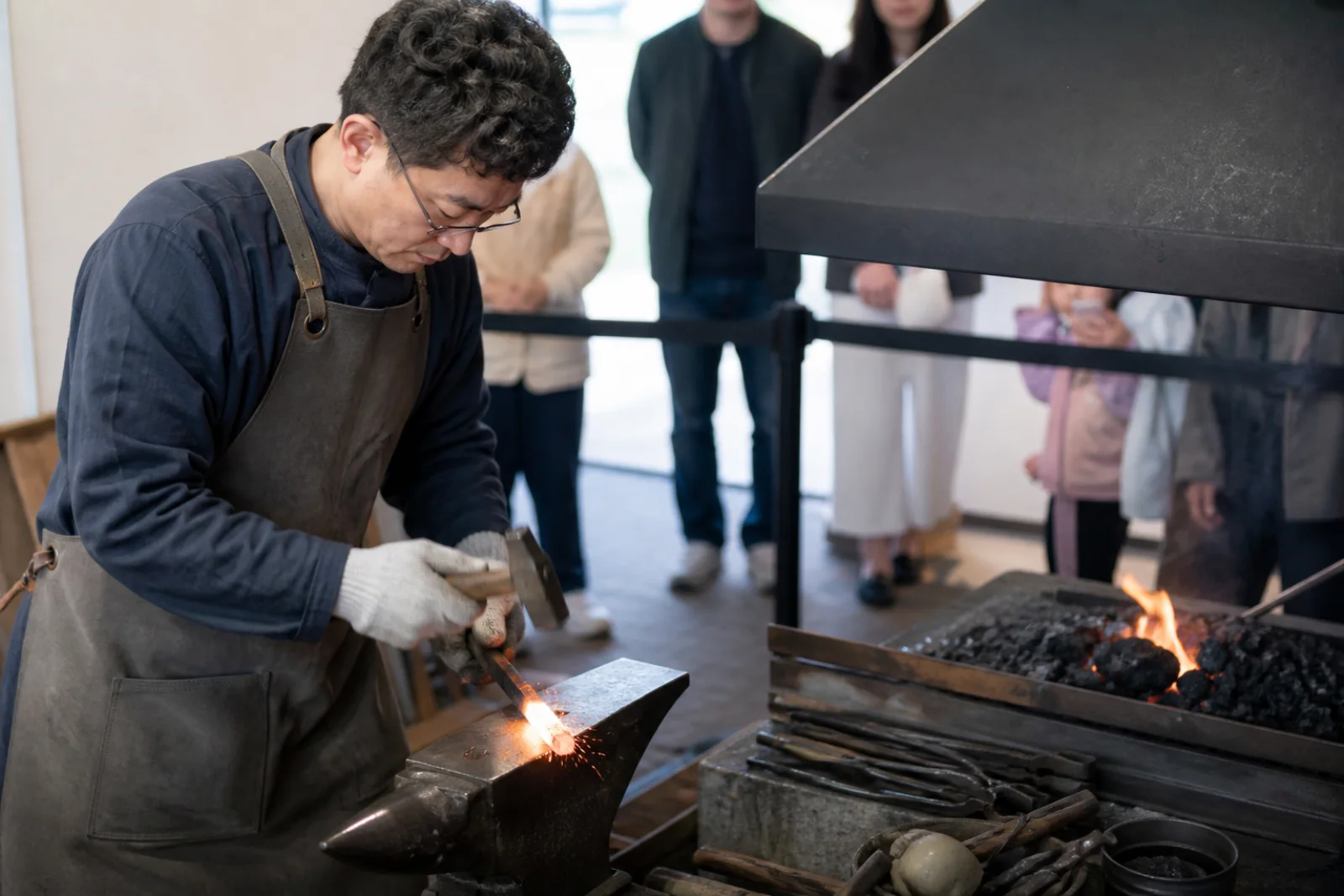 A contemporary museum workshop demonstrating traditional iron shaping beside replica tools