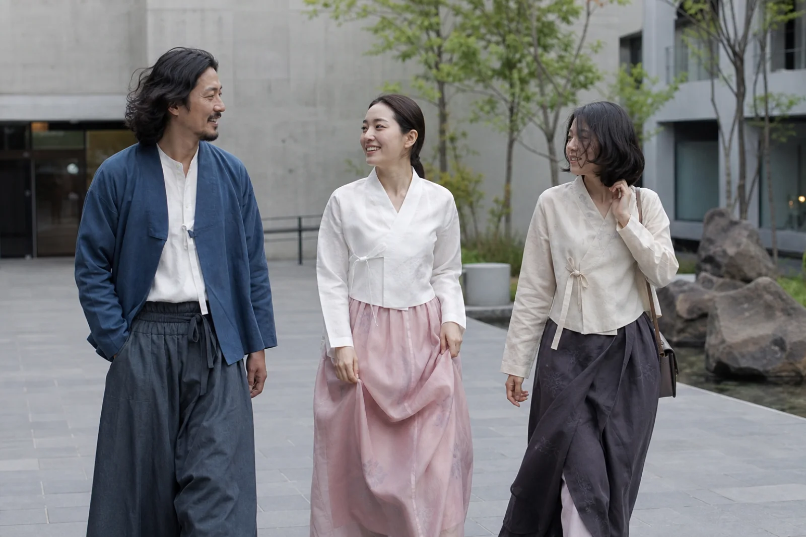 Friends in contemporary hanbok walking naturally through a modern Seoul courtyard