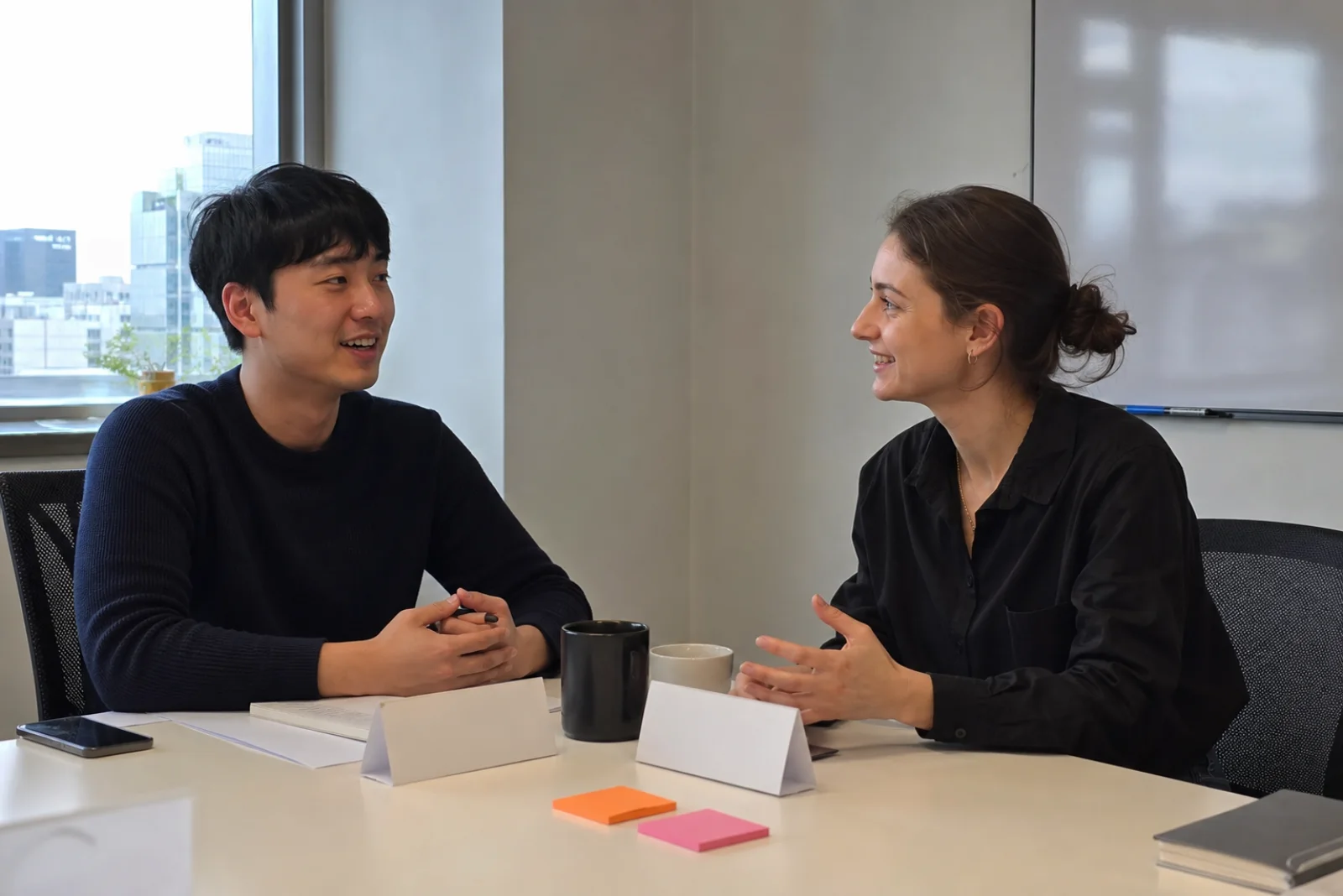 Two colleagues exchanging introductions across a small office table in Seoul