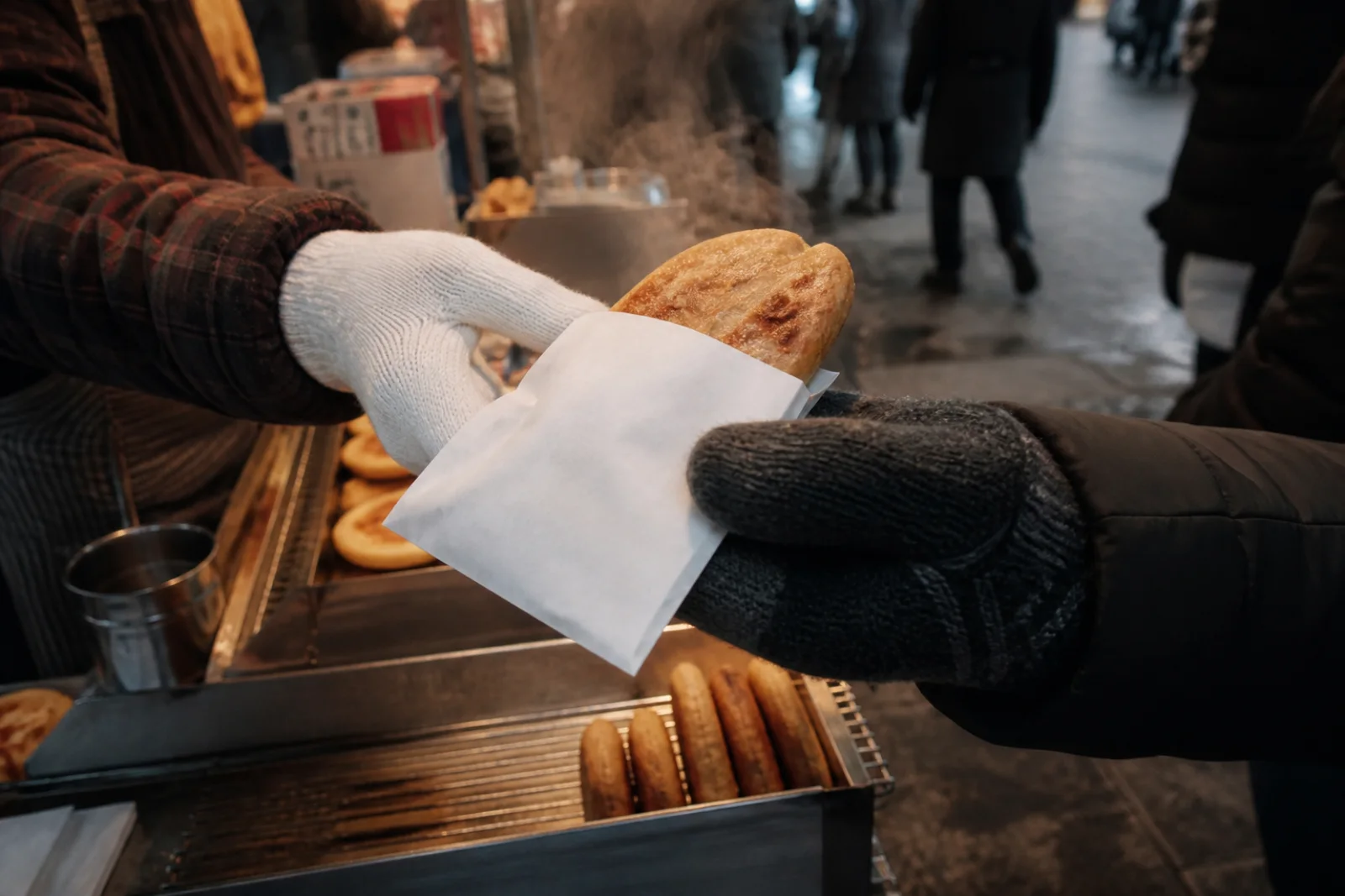 Hands receiving a hot winter snack from a small Seoul street stall