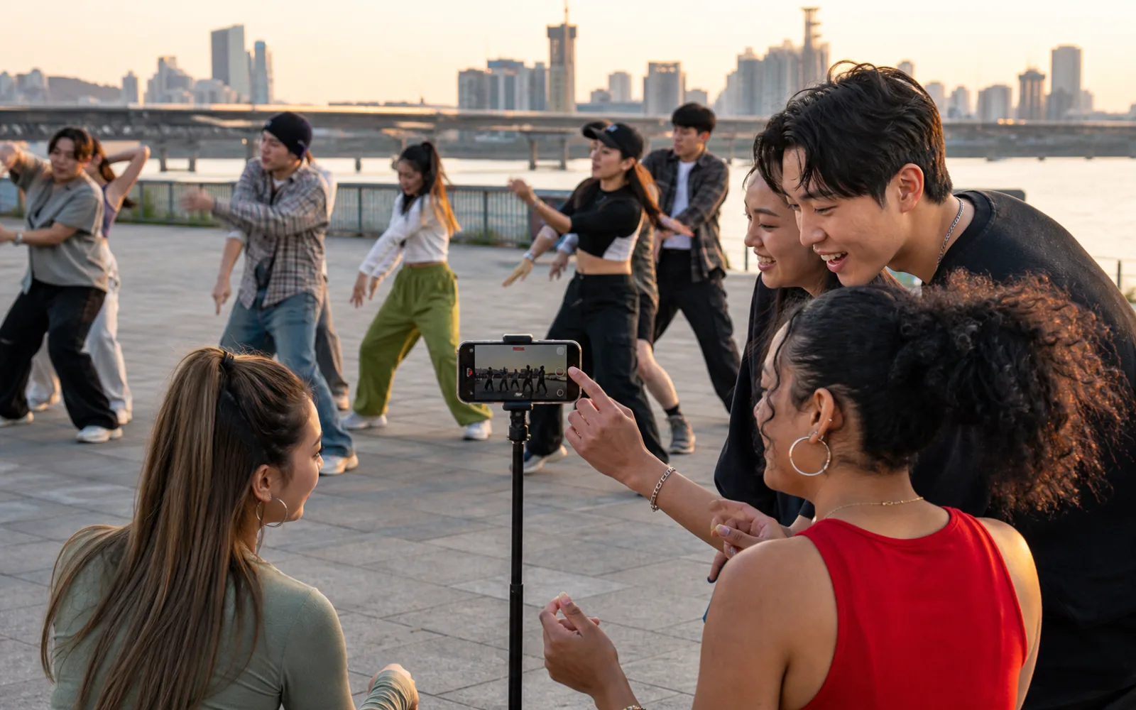 A diverse group filming a dance practice beside the Han River in Seoul