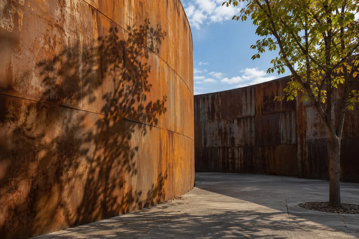 Conceptual curved weathered steel beside a tree, not the actual park
