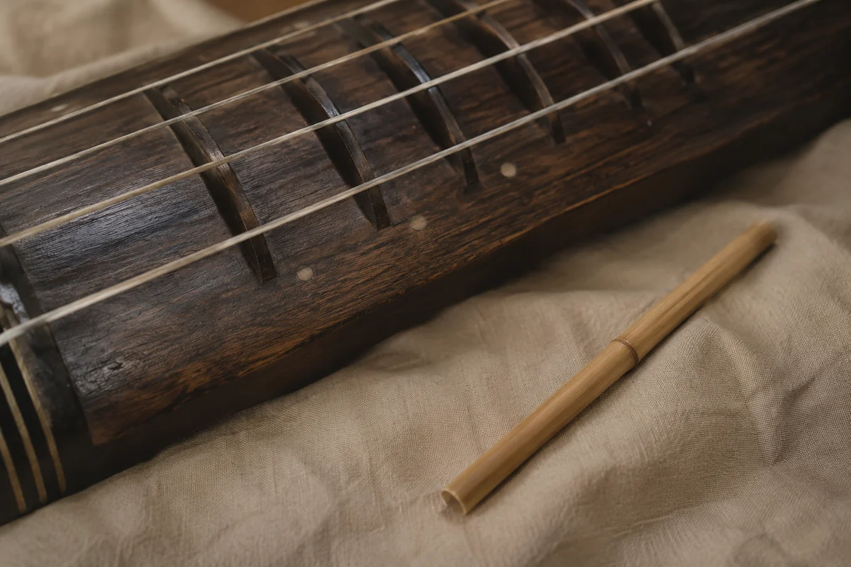 Conceptual cropped fretted wooden zither beside a bamboo stick