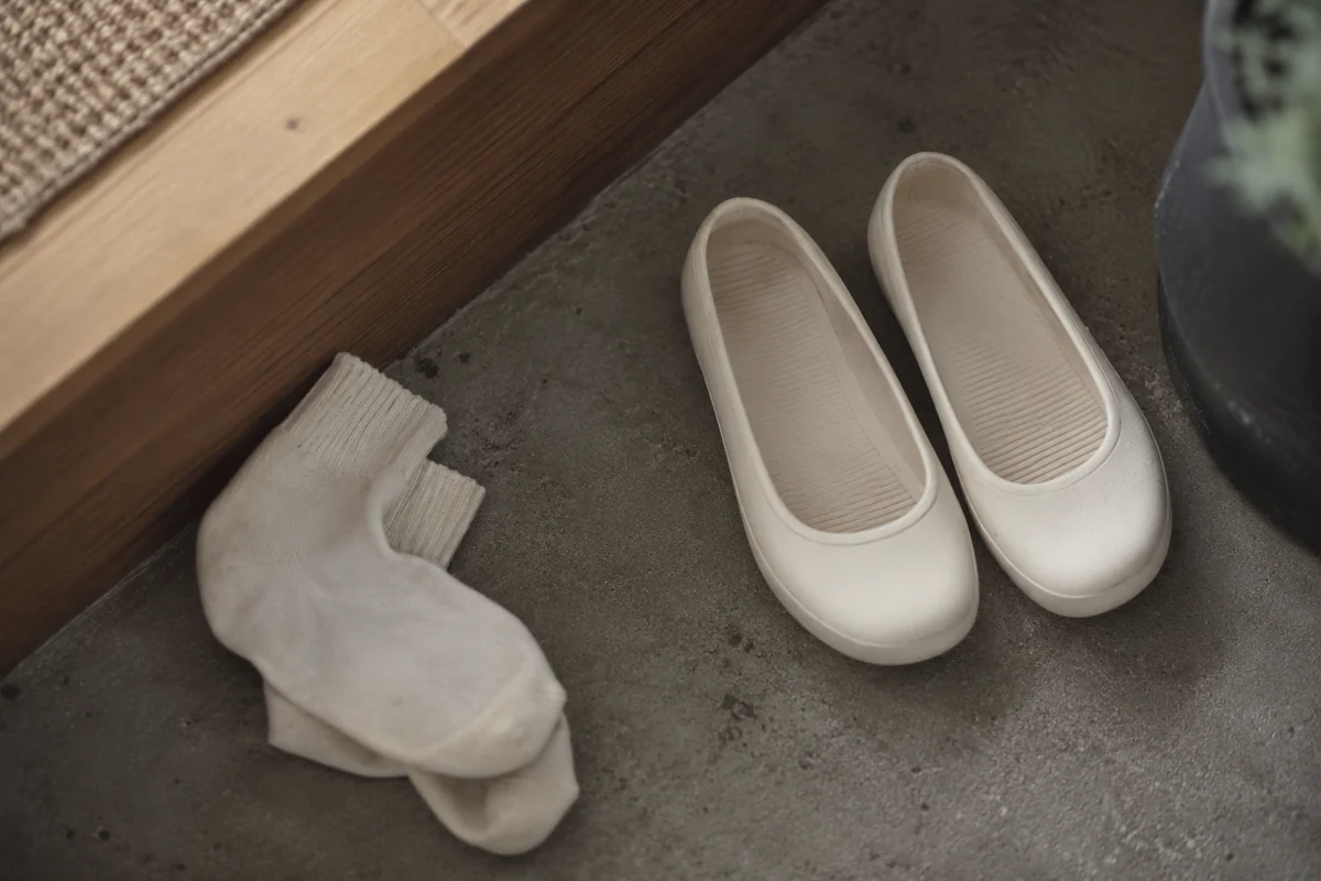 Conceptual plain cream-colored low rubber shoes beside socks