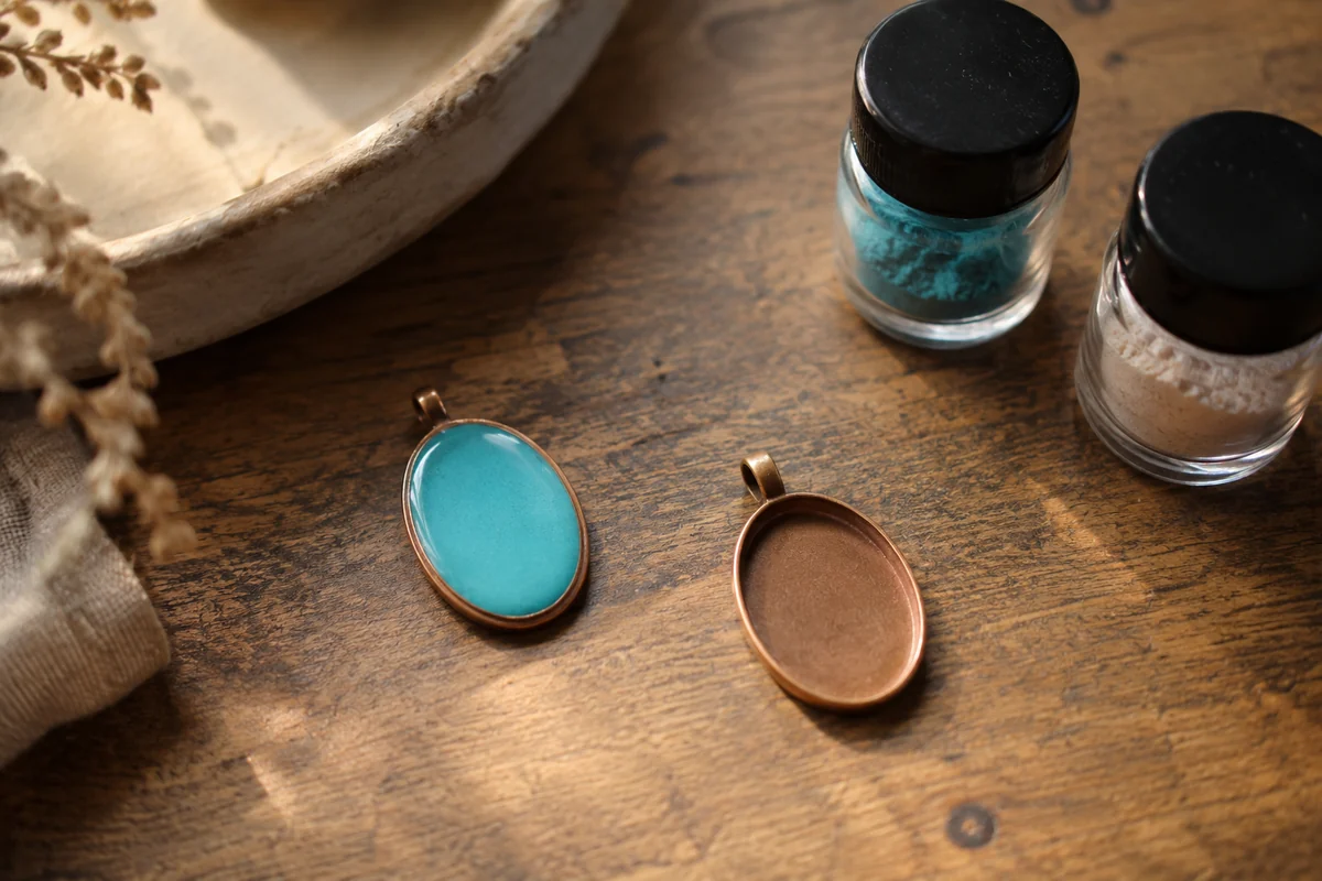 Conceptual plain turquoise enamel pendant beside a blank copper base