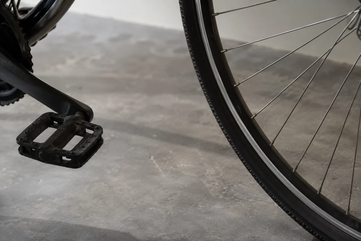 Conceptual bicycle wheel, spokes and pedal on a gray floor